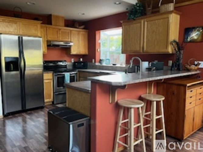A kitchen with a refrigerator, stove, and bar stools.