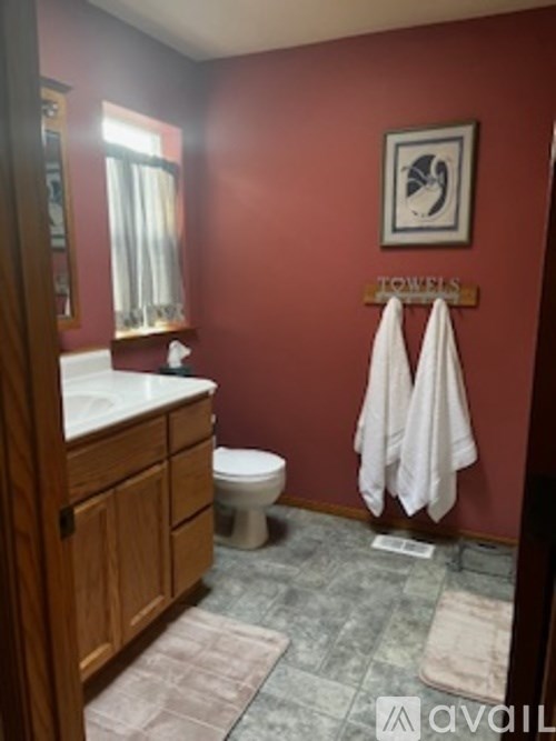 A red bathroom with a toilet, sink, and towels.