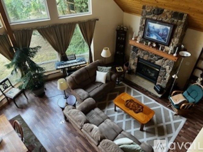 A living room with a stone fireplace and a television above it.