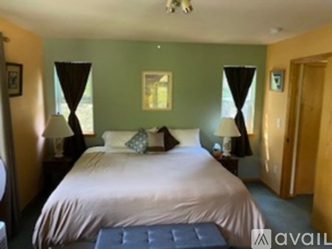 A bedroom with a large bed and two lamps.