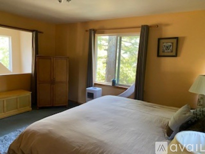 A bedroom with a large bed and a window with curtains.