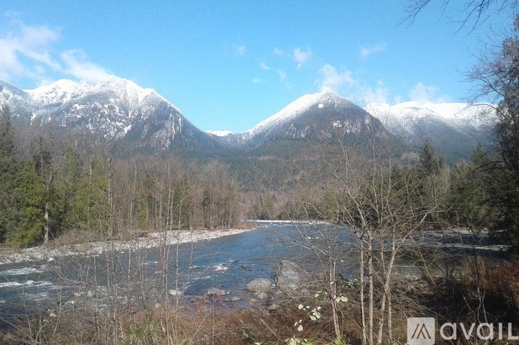 A river flows through a valley with snow-capped mountains in the background.