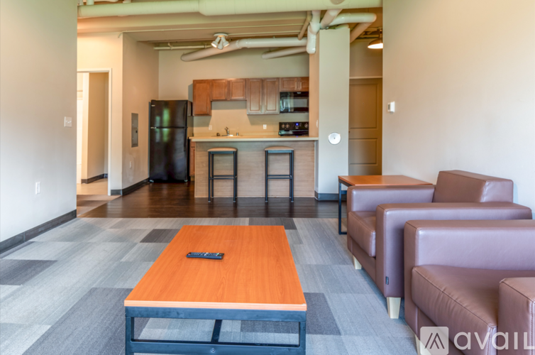 A modern living room with a kitchen in the background.