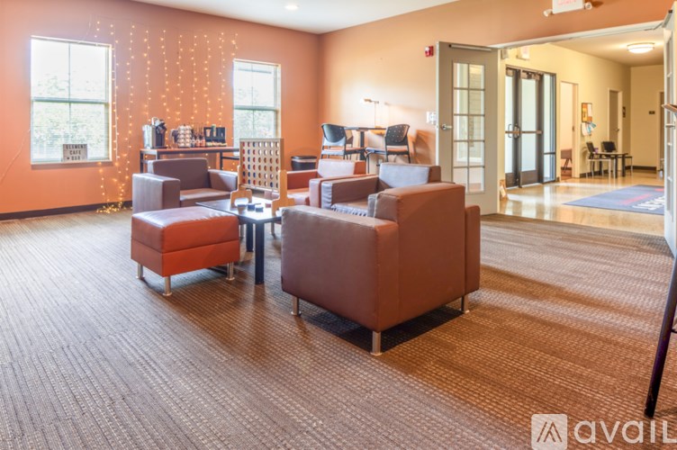 A room with orange walls and a carpeted floor with a couch and a table.