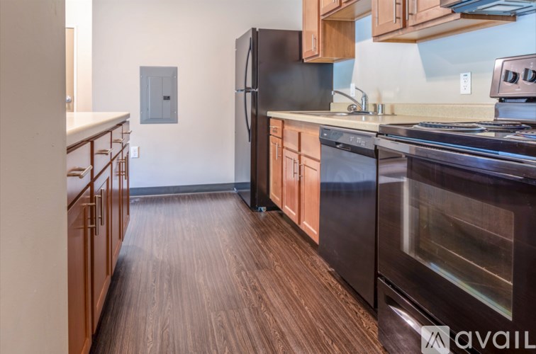 A kitchen with wooden floors and a black refrigerator.