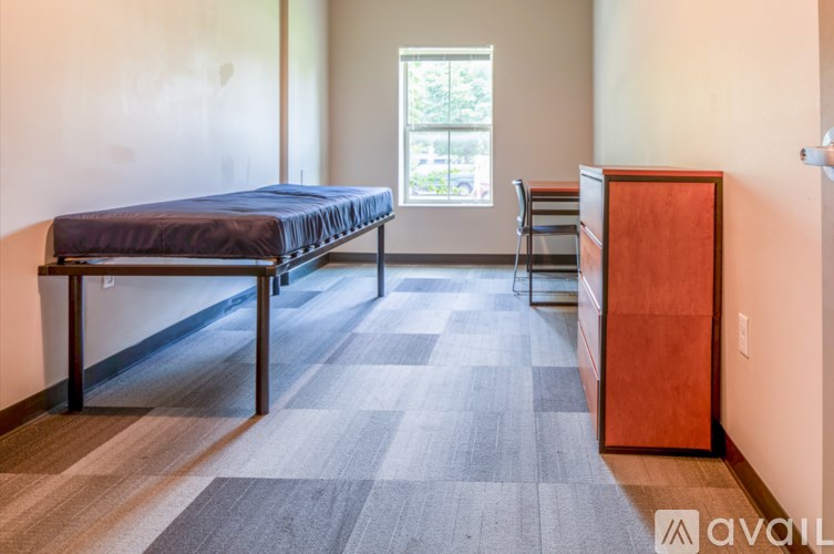 A bedroom with a bed, chair, and dresser.
