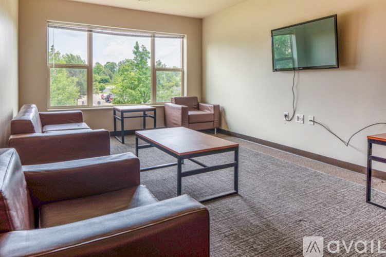 A living room with brown leather furniture and a flat screen TV mounted on the wall.