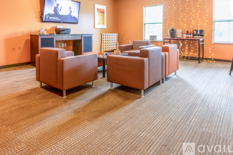 A living room with orange chairs and a television on the wall.