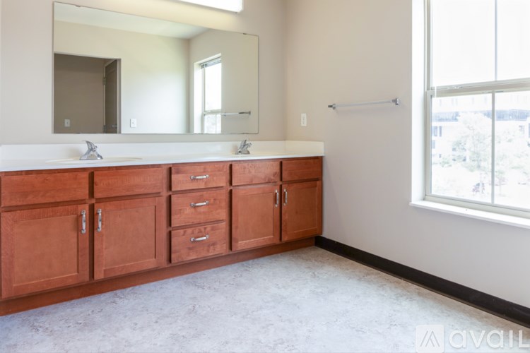 A bathroom with a white counter top and brown cabinets.