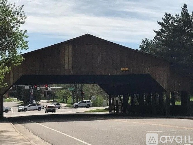 A large wooden covered bridge spans across a road.