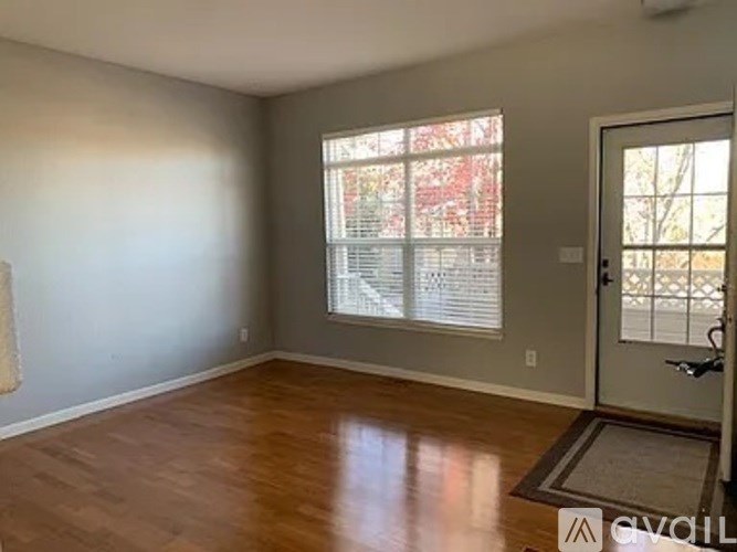 A room with a wooden floor and a door leading to a balcony.