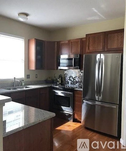 A kitchen with wooden cabinets and a stainless steel refrigerator.