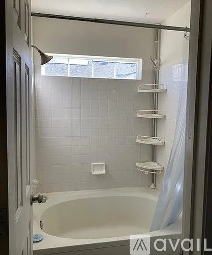 A white bathroom with a tub and a window.