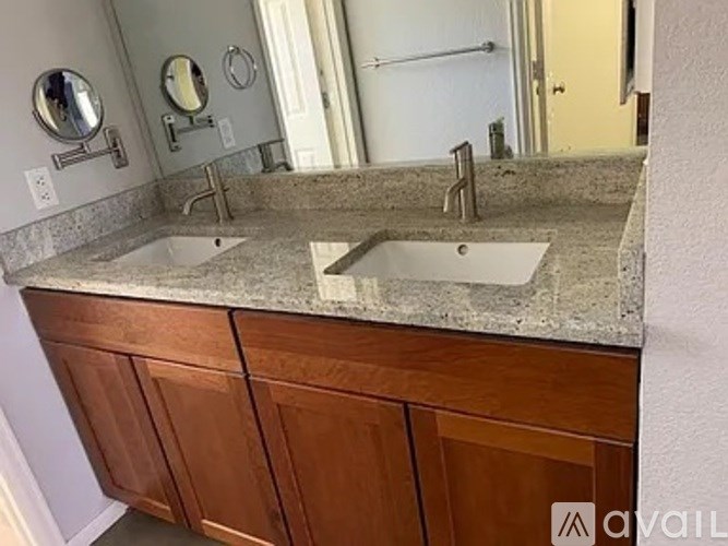 A bathroom with a granite countertop and two sinks.