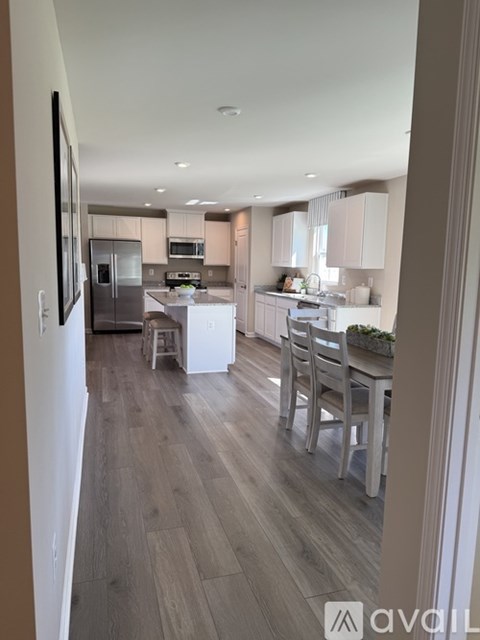 A modern kitchen with wooden floors and white cabinets.