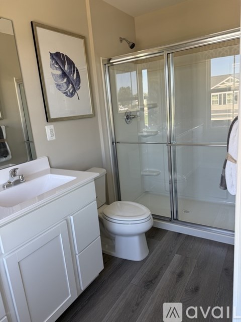 A bathroom with a white toilet, sink, and a framed leaf picture on the wall.