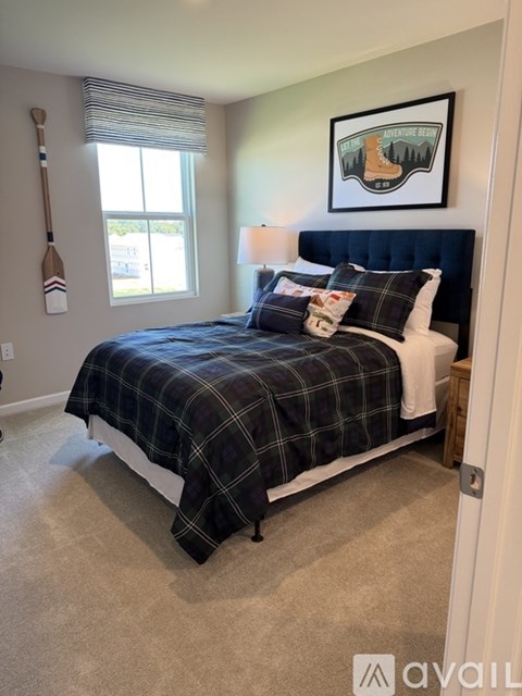 A bedroom with a bed, pillows, and a picture on the wall.