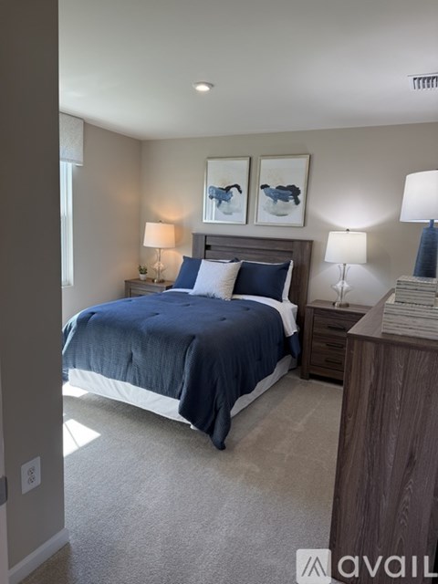 A bedroom with a bed, nightstands, and two framed pictures on the wall.