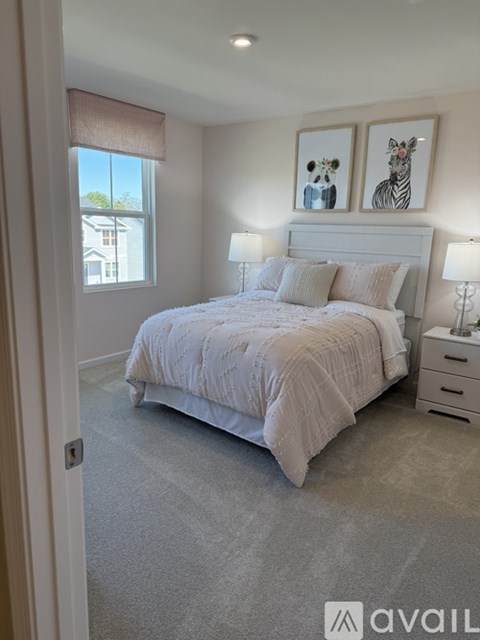 A bedroom with a large bed, two lamps, and two framed pictures of animals on the wall.