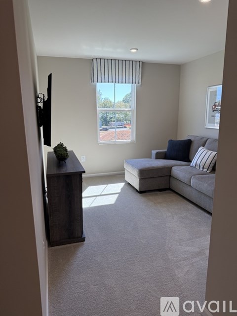 A living room with a grey couch and a flat screen TV mounted on the wall.