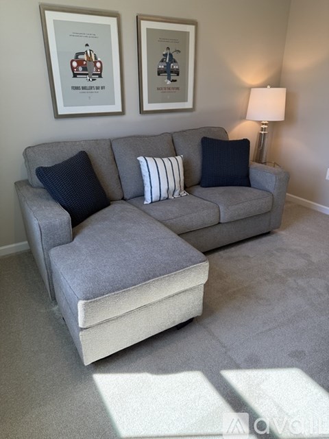 A grey couch with a pillow and a lamp on the side.