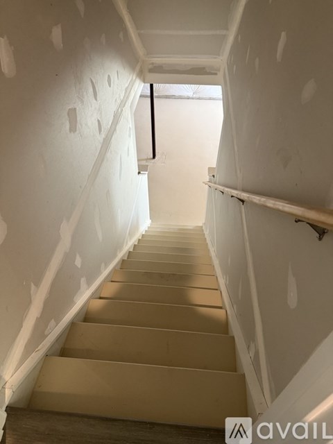 A staircase with a wooden handrail and steps leading upwards.