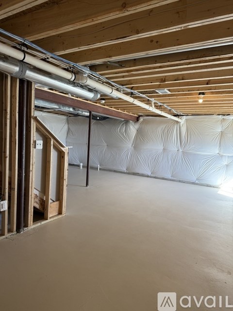 A room under construction with exposed wooden beams and insulation on the walls.
