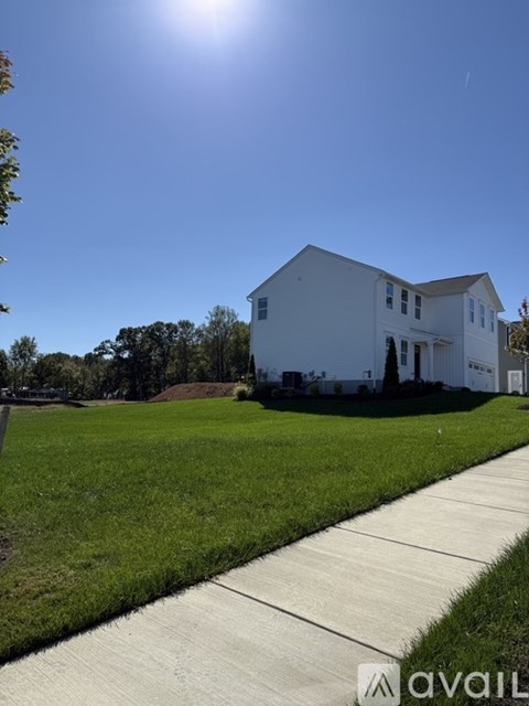 A white house with a green lawn in front of it.