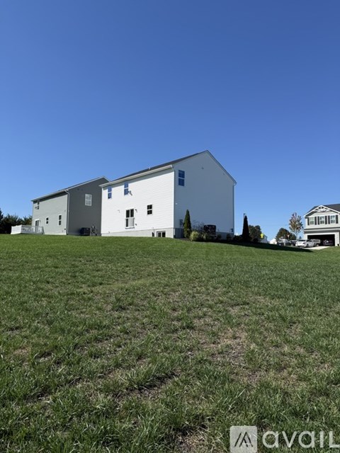 A large white building with a grey roof is situated on a grassy field.
