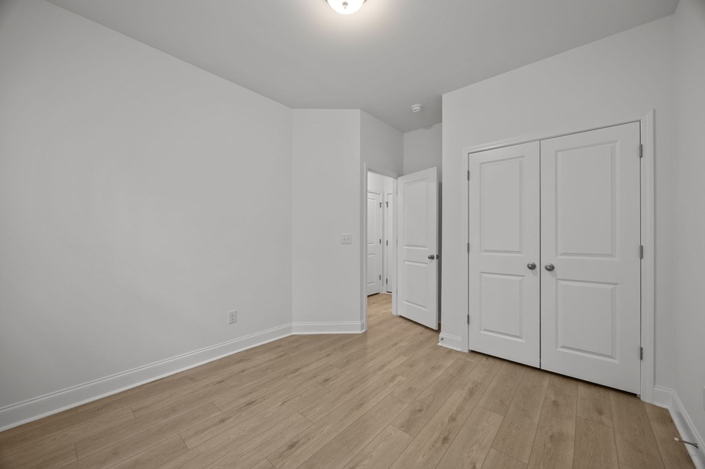 A room with white walls and wooden flooring with two white doors.