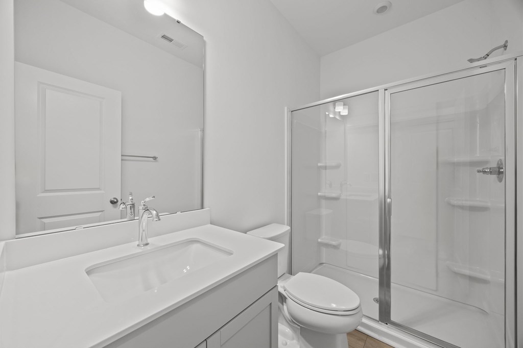 A white bathroom with a sink, toilet, and shower.