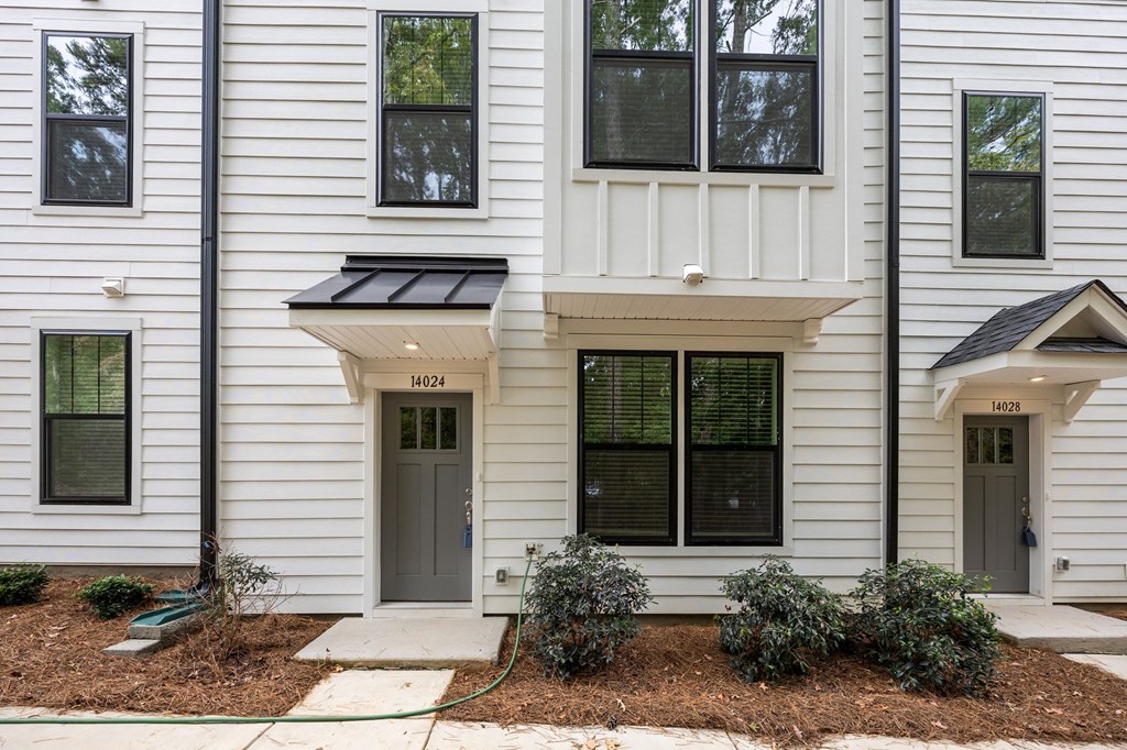 A white two story house with a grey door and windows.