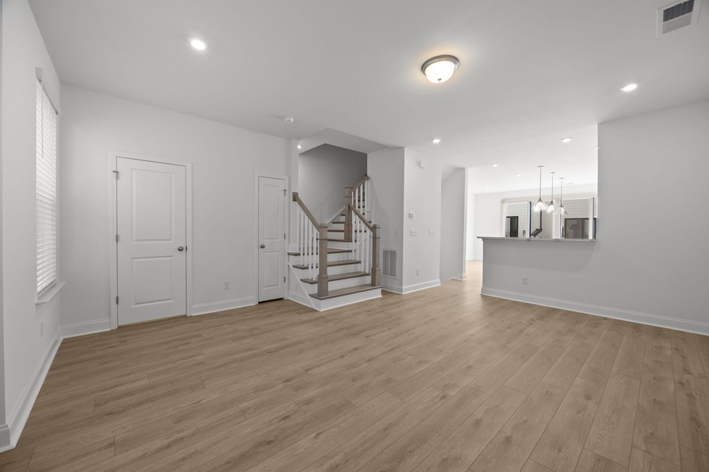 A spacious room with wooden floors and a staircase.