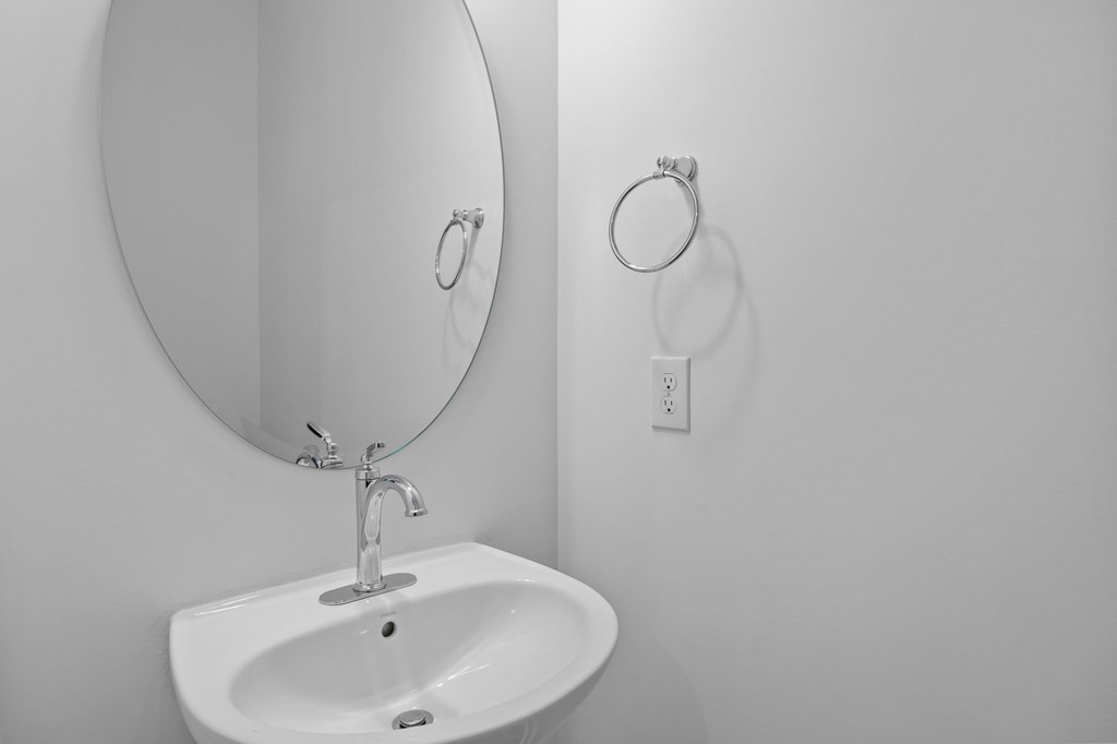 A white sink with a round mirror above it.