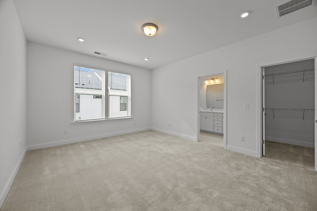 A spacious room with a carpeted floor and a window with blinds.