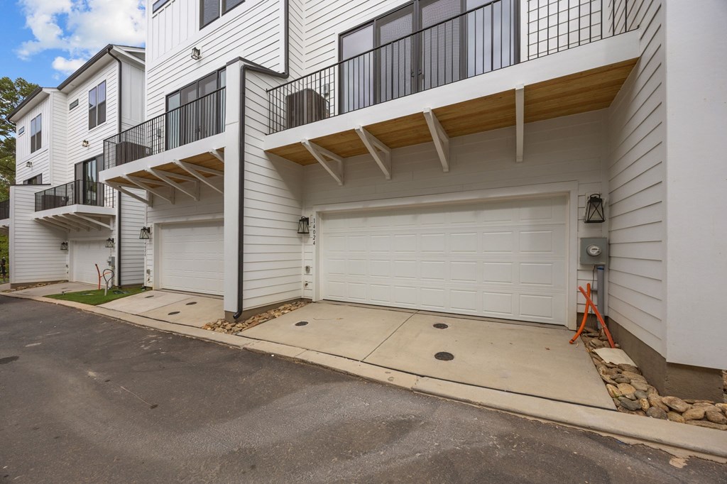 A white two-story apartment building with a balcony on the second floor.