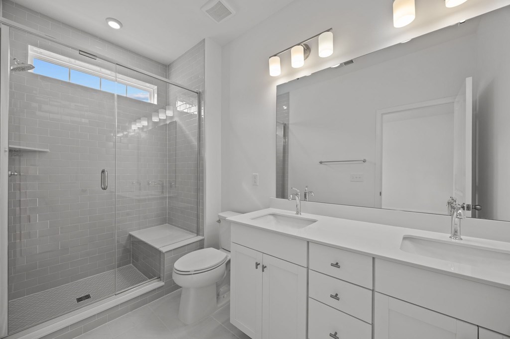 A white bathroom with a toilet, sink, and shower.