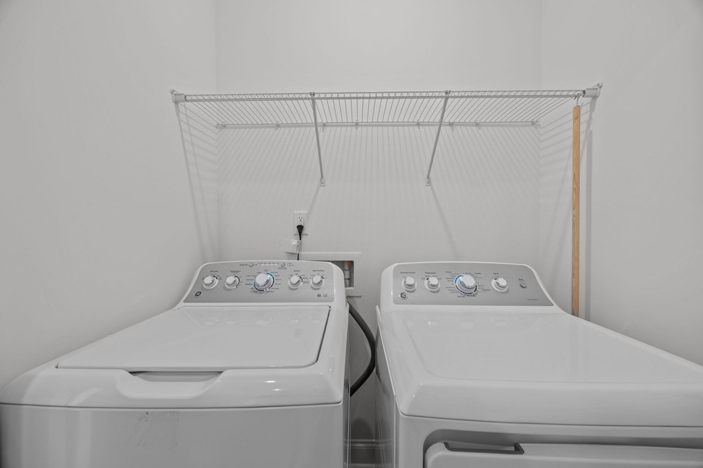 Two white washing machines in a laundry room.