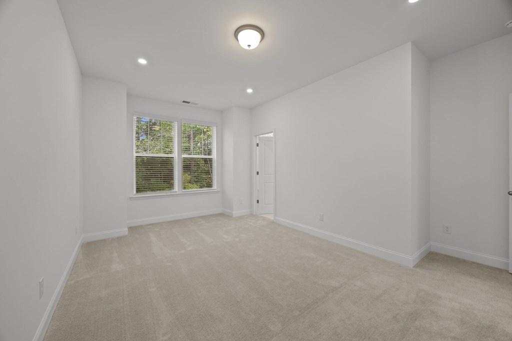 A room with a carpeted floor and a window with blinds.