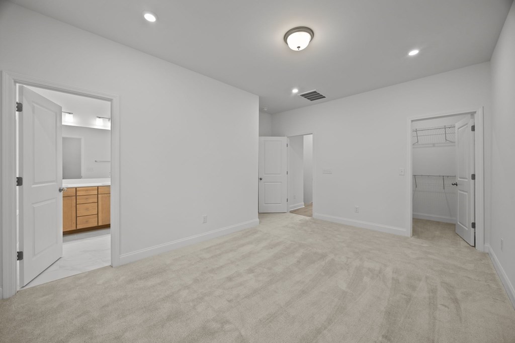 A spacious room with white walls and carpeted floor.