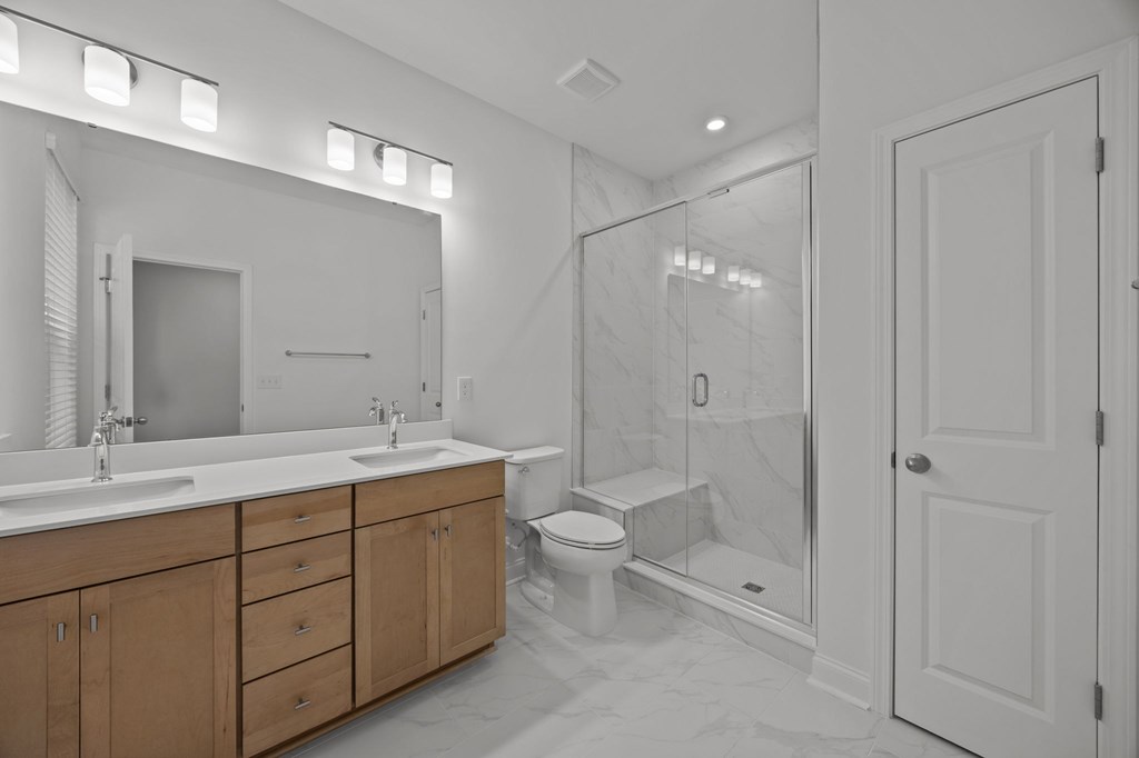 A bathroom with a walk-in shower and a vanity with two sinks.