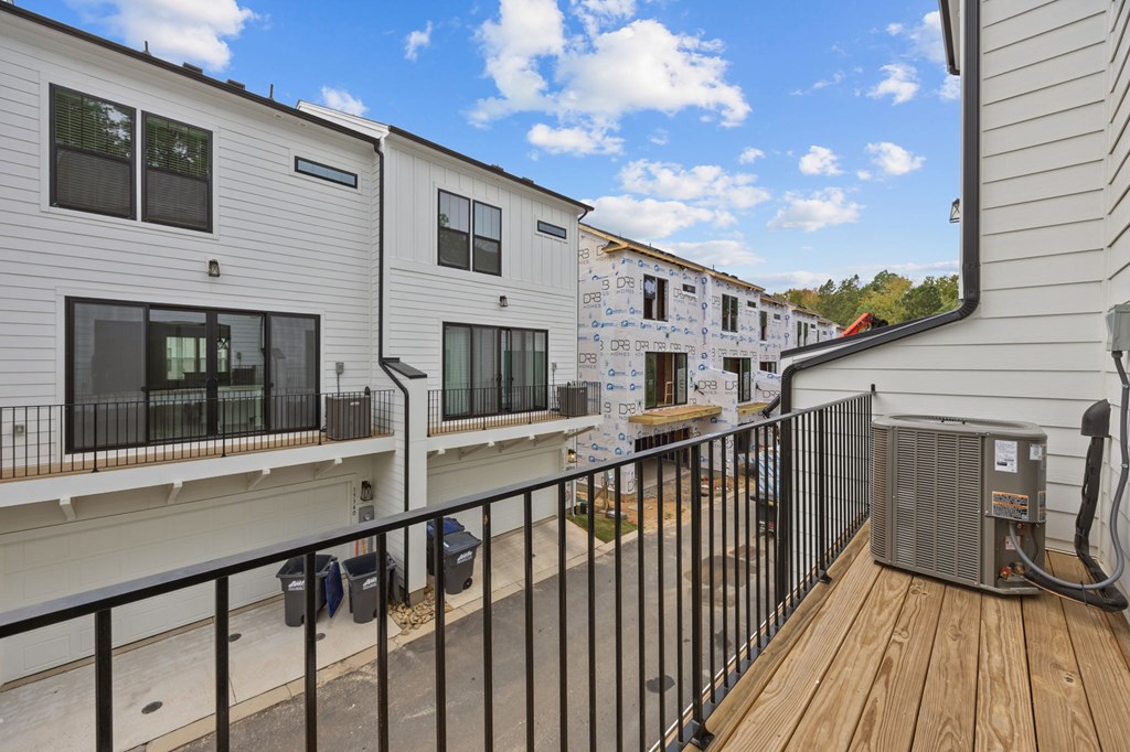 A row of white houses with black railings and a wood deck.