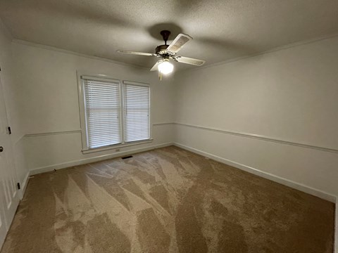 A room with a ceiling fan and carpeted floor.