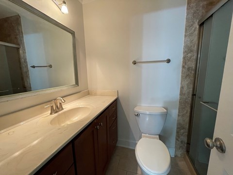 A bathroom with a toilet, sink, and mirror.