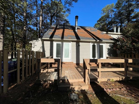 A house with a grey exterior and a red roof is surrounded by trees.