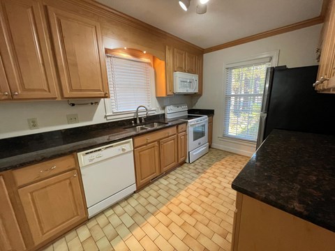 A kitchen with wooden cabinets and black countertops.