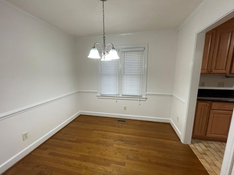 A room with wooden floors and a window with blinds.