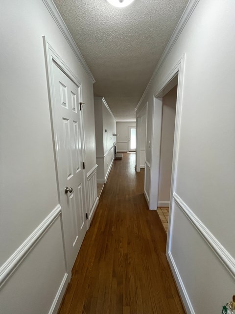 A long hallway with white walls and wood floors.