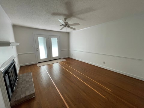 A room with a ceiling fan and wooden flooring.