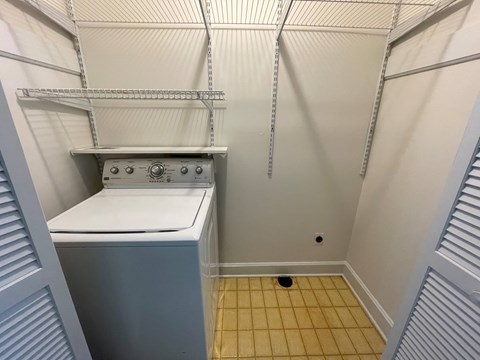 A small, white, built-in dishwasher is in a narrow kitchen.